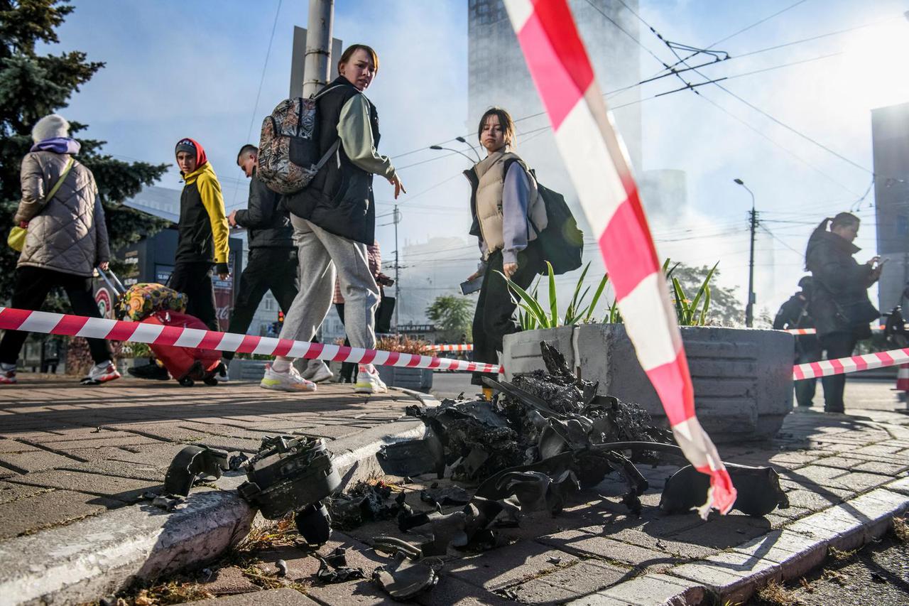 Local residents look at parts of an unmanned aerial vehicle after a Russian drone strike in Kyiv