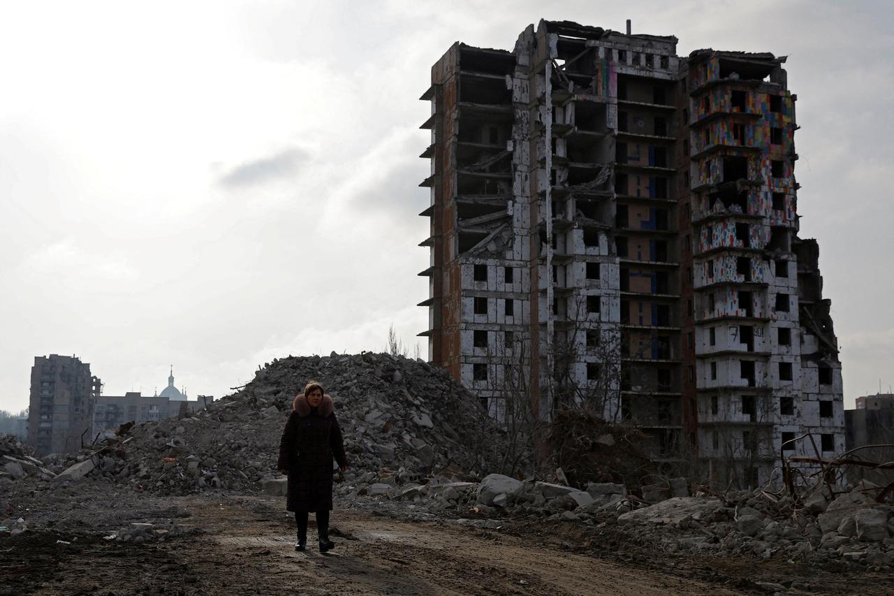 FILE PHOTO: Tatiana Bushlanova walks next to the ruins of her apartment block, demolished due to heavy damage, in Mariupol