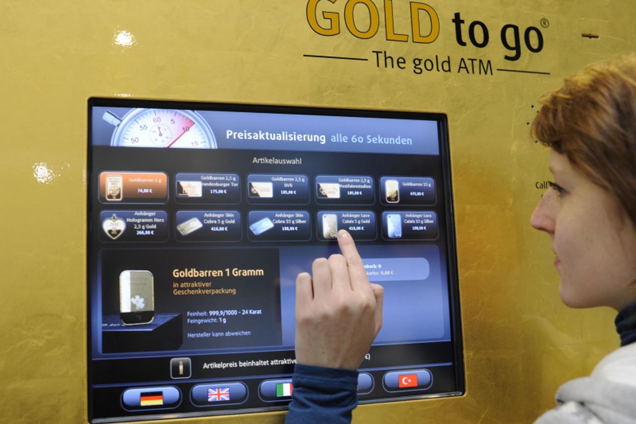 'Ulrike Hoessl, employee of German company Desko, poses beside a \'Gold to go\' machine during preparations at the CeBit computer fair in Hanover, March, 5, 2012. Desko is responsible for the security