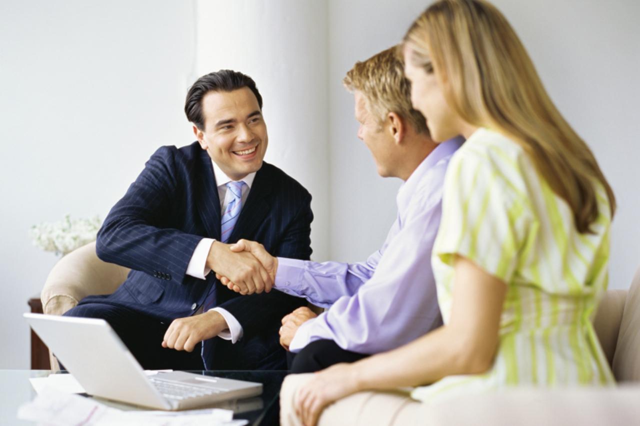 'male real estate agent shaking hands with a mid adult man'