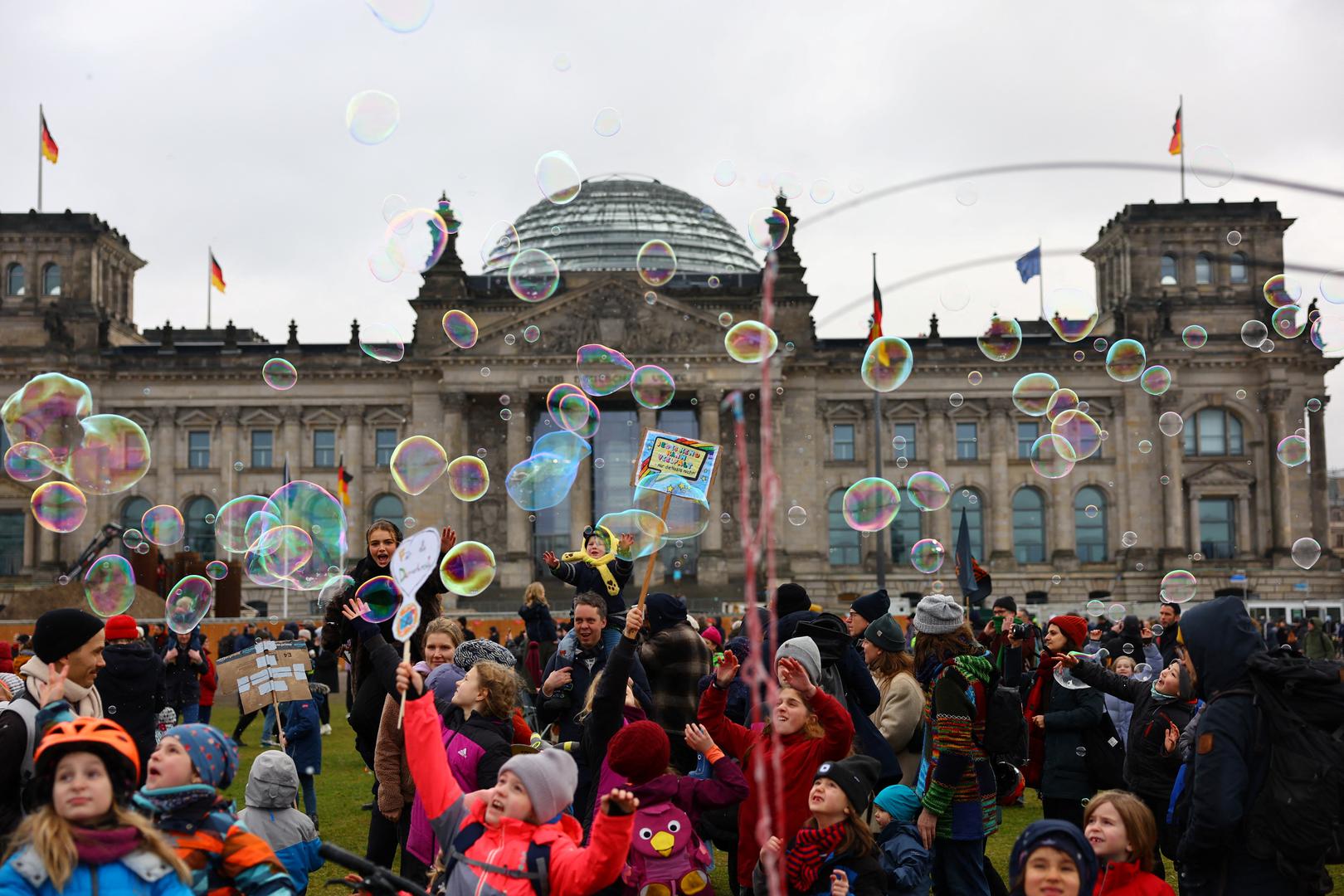 Children play with soap bubbles as people gather outside the Reichstag building, during a rally of the broad alliance "Hand in Hand" under the slogan "Wir sind die Brandmauer" ("We are the Firewall") to protest against right-wing extremism and for the protection of democracy, in Berlin, Germany February 3, 2024.  REUTERS/Fabrizio Bensch Photo: Fabrizio Bensch/REUTERS