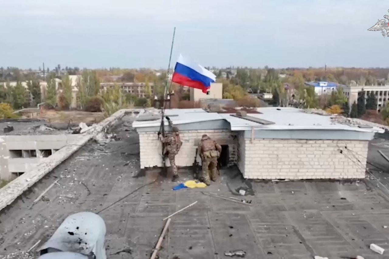 Russian service members hoist a Russian flag on the top of a building in Selydove