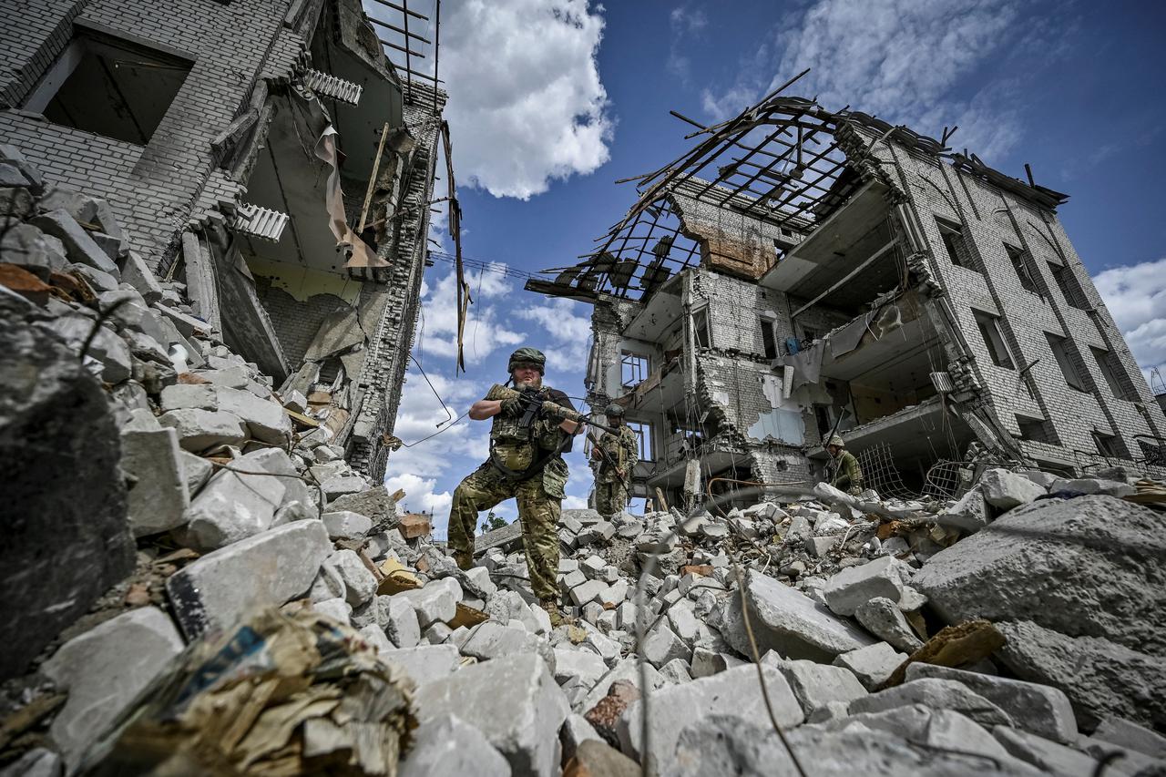 Ukrainian servicemen patrol an area heavily damaged by Russian military strikes in the town of Orikhiv