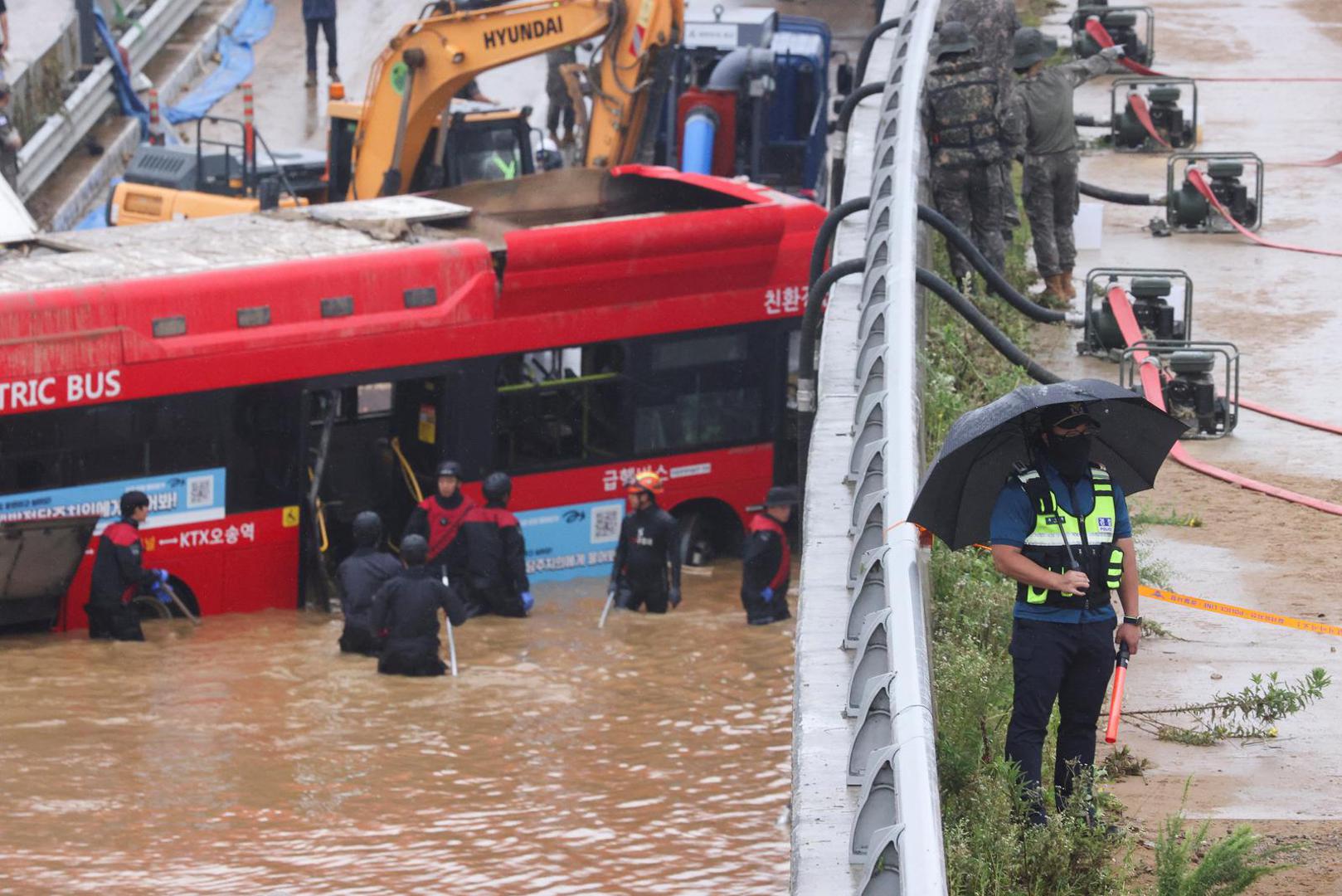 A police officer stands next to water pumps as rescue workers take part in a search and rescue operation near an underpass that has been submerged by a flooded river caused by torrential rain in Cheongju, South Korea, July 16, 2023.   REUTERS/Kim Hong-ji Photo: KIM HONG-JI/REUTERS