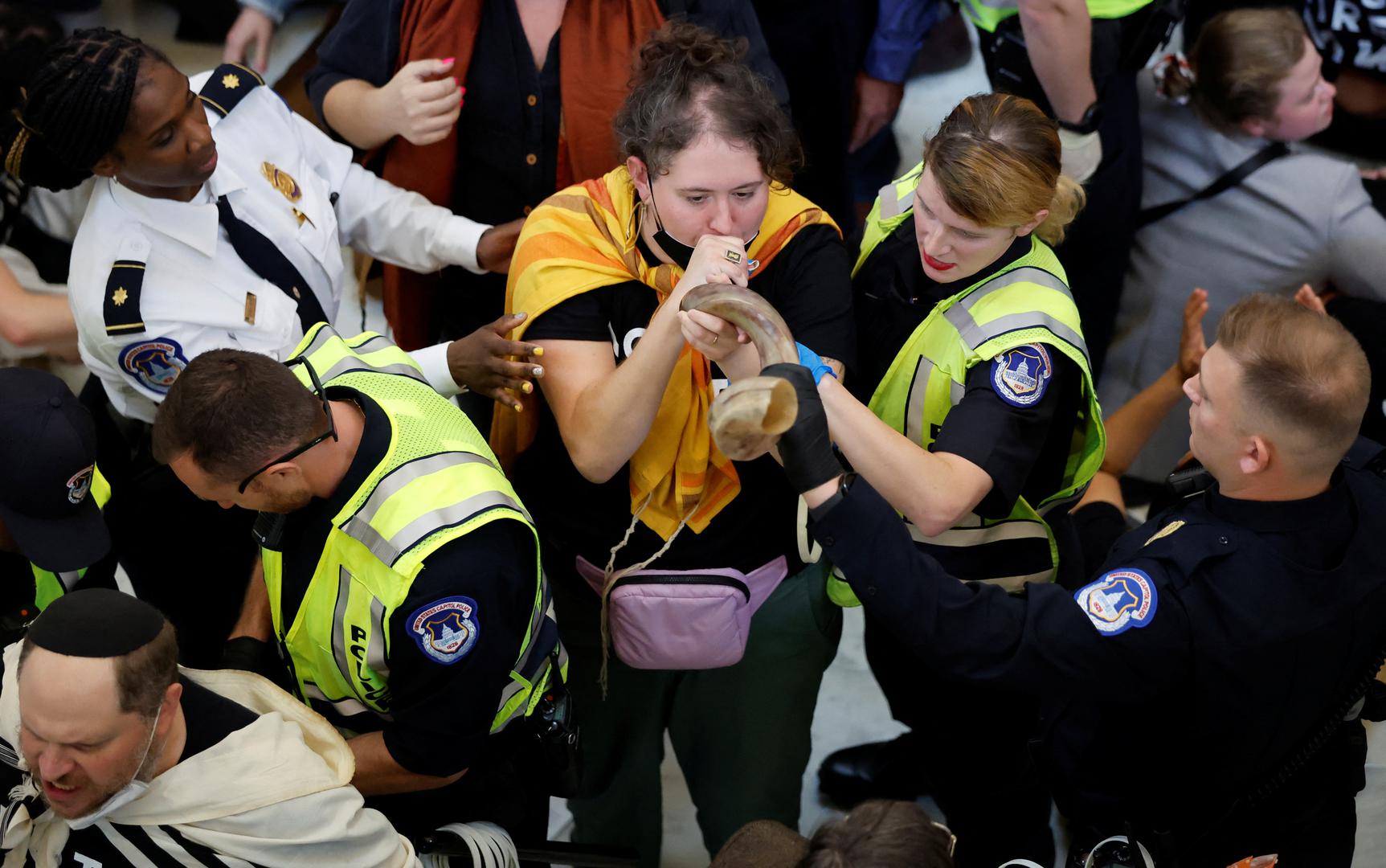 A protestor continues to blow on a shofar horn as she is grabbed and detained by several U.S. Capitol police officers during a civil disobedience action organized by a group called "Jewish Voice for Peace," calling for a cease fire in Gaza, while occupying the rotunda of the Cannon House office building on Capitol Hill in Washington, U.S., October 18, 2023. REUTERS/Jonathan Ernst Photo: JONATHAN ERNST/REUTERS