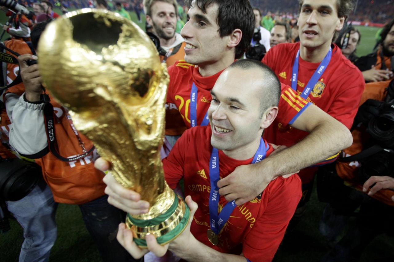 'Spain\'s Andres Iniesta holds the World Cup trophy after the 2010 World Cup final soccer match between Netherlands and Spain at Soccer City stadium in Johannesburg July 11, 2010.               REUTER