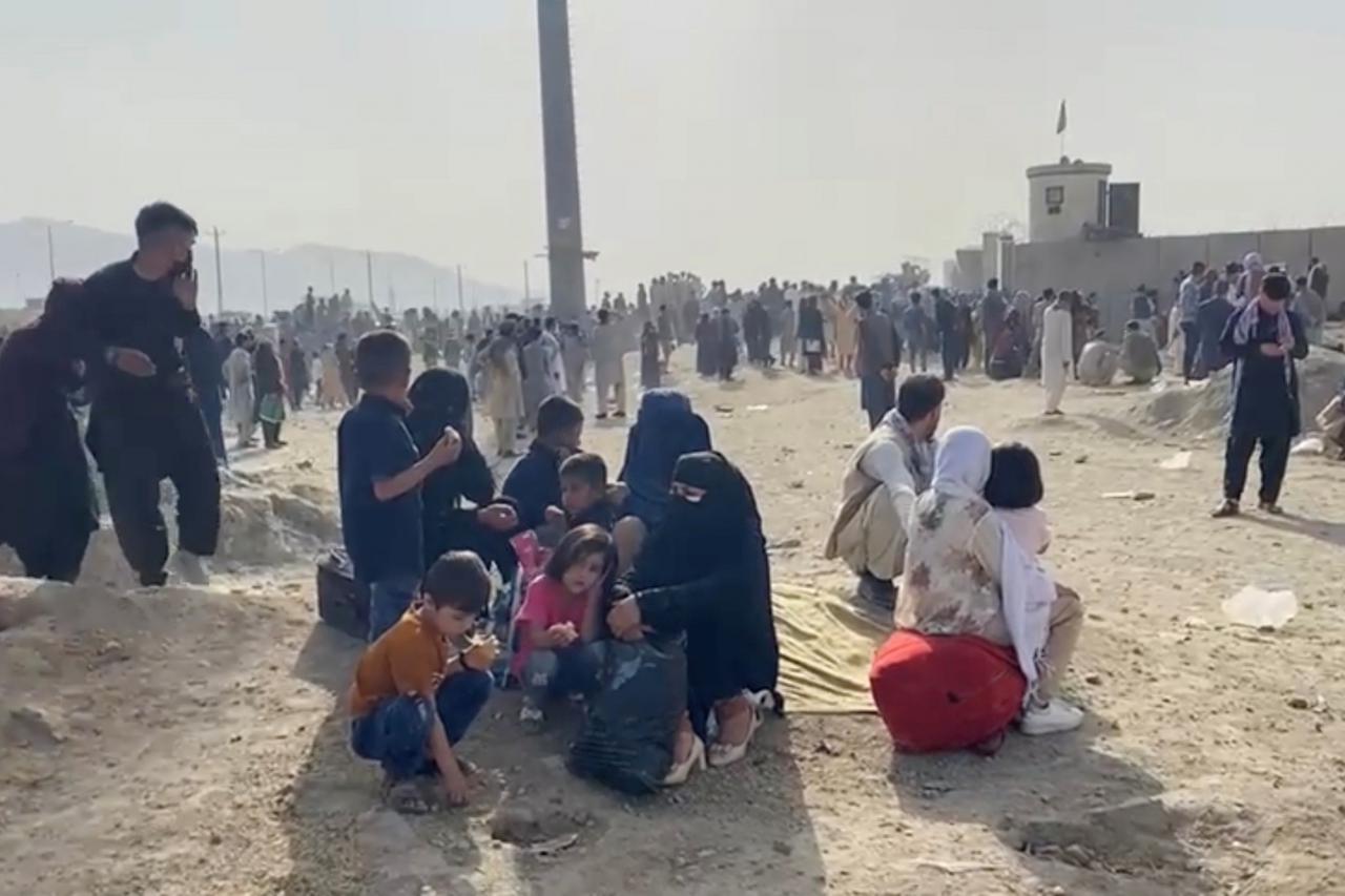 People gathered outside the airport react to gunfire, in Kabul