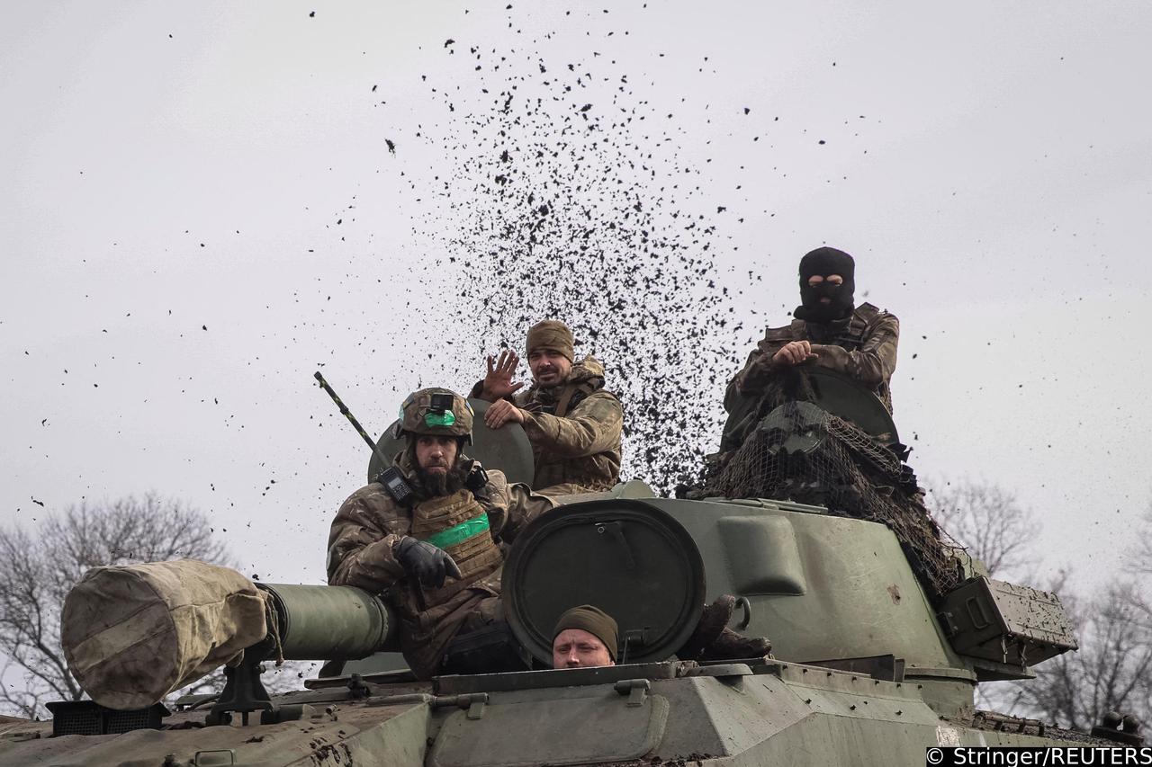 Ukrainian service members ride a self-propelled howitzer near Bakhmut