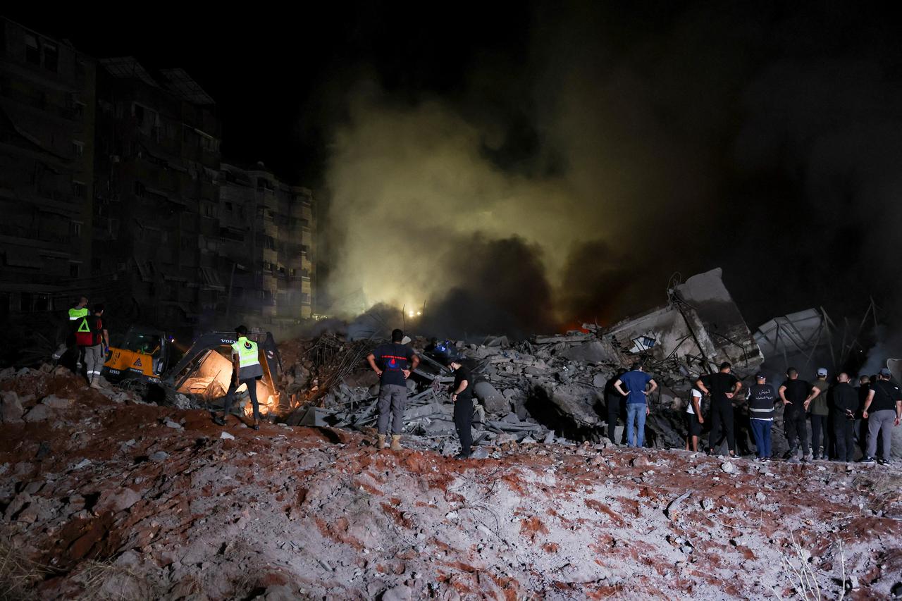 People inspect damage at the site of an Israeli strike, in Beirut