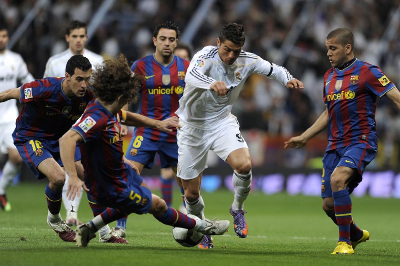 'Real Madrid\'s Portuguese Cristiano Ronaldo (C) vies for the ball with Barcelona\'s captain Carles Puyol (2L) and Barcelona\'s Brazilian defender Dani Alves (R) during the \'El Clasico\' Spanish Leag