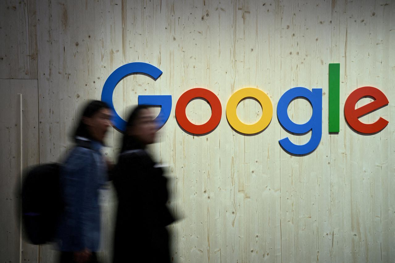 FILE PHOTO: People walk next to a Google logo at Hannover Messe, Germany