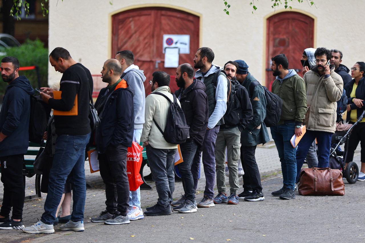 Migrants queue at the arrival centre for asylum seekers at Reinickendorf district in Berlin