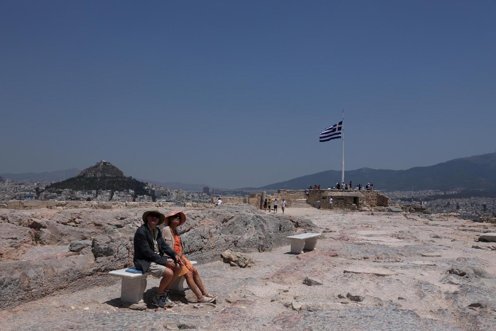 Visitors sit on a bench on the Acropolis hill, during a heatwave in Athens, Greece, July 13, 2023. REUTERS/Louiza Vradi Photo: LOUIZA VRADI/REUTERS