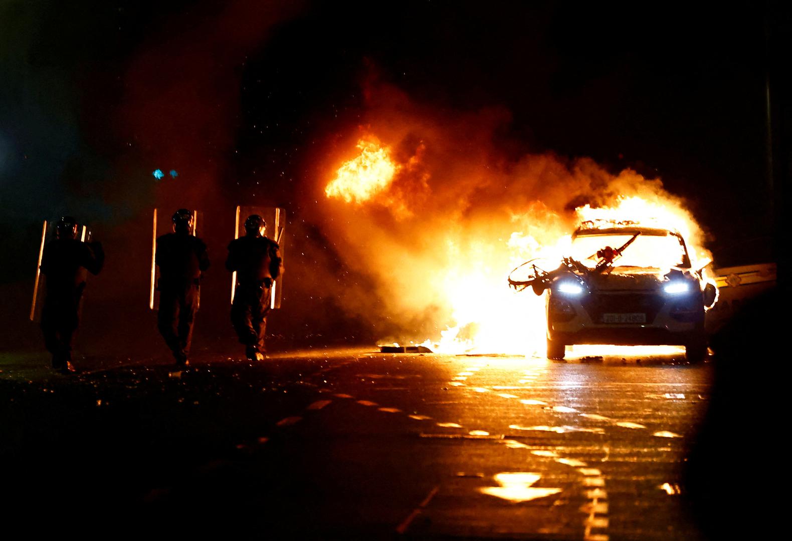 Riot police walks next to a burning police vehicle, near the scene of a suspected stabbing that left few children injured in Dublin, Ireland, November 23, 2023. REUTERS/Clodagh Kilcoyne      TPX IMAGES OF THE DAY Photo: Clodagh Kilcoyne/REUTERS