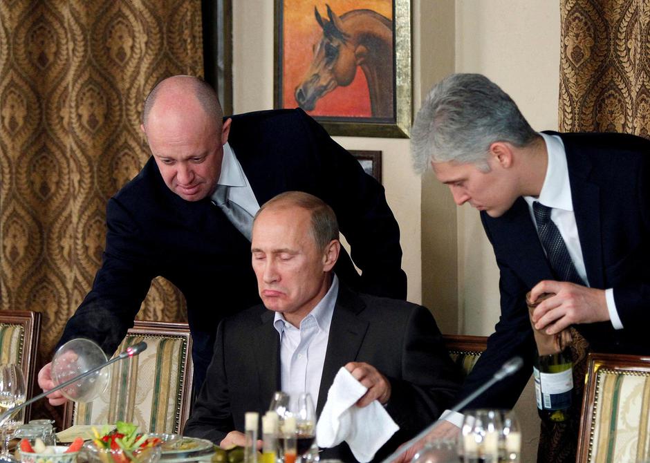 FILE PHOTO: Yevgeny Prigozhin assists Russian Prime Minister Vladimir Putin during a dinner with foreign scholars and journalists at the restaurant Cheval Blanc on the premises of an equestrian complex outside Moscow