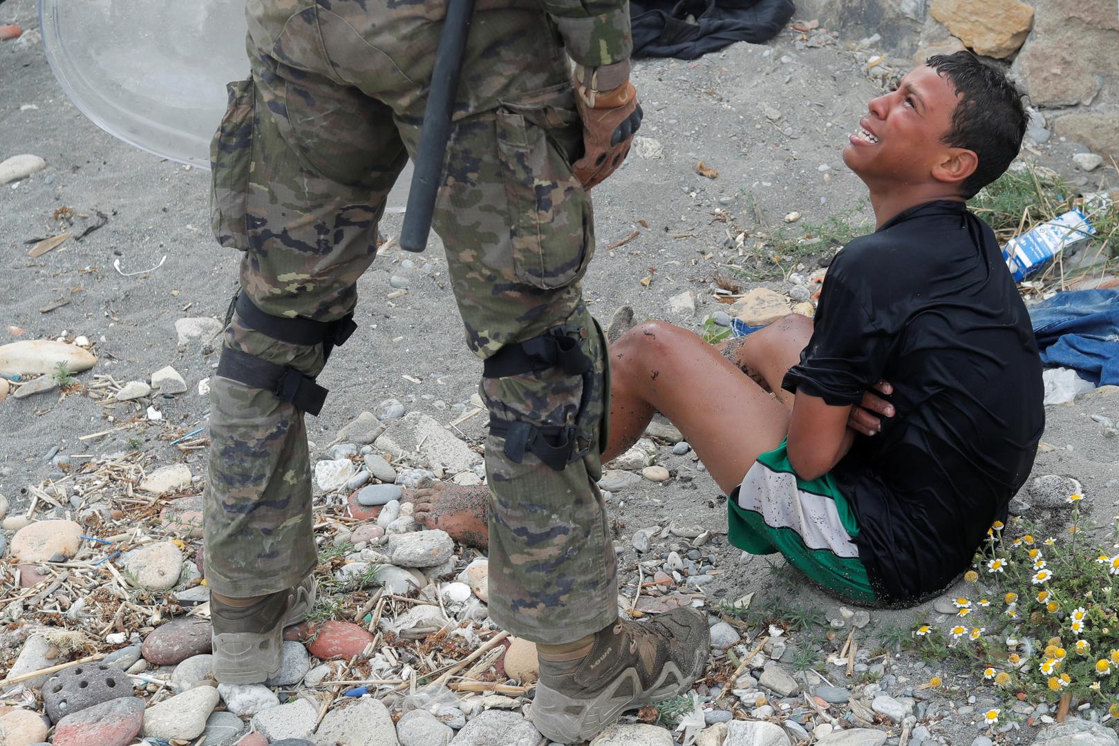 Thousands of migrants cross the Spanish-Moroccan border A Moroccan boy cries as he is helped by a Spanish soldier after he swam using bottles as a float, at El Tarajal beach, near the fence between the Spanish-Moroccan border, after thousands of migrants swam across the border, in Ceuta, Spain, May 19, 2021. REUTERS/Jon Nazca JON NAZCA