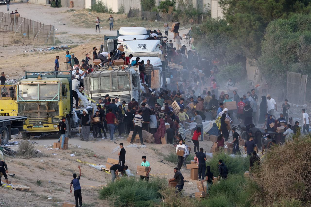 FILE PHOTO: Palestinians climb onto trucks to grab aid that was delivered into Gaza through a U.S.-built pier, as seen from central Gaza Strip