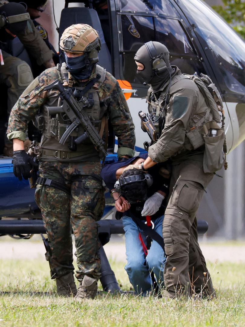 A 26-year-old Syrian man, who is the suspect in custody for a stabbing rampage in the western German city of Solingen in which several individuals were killed, is escorted by police on his way to the Federal Public Prosecutor in Karlsruhe, Germany, August 25, 2024. REUTERS/Heiko Becker Photo: Heiko Becker/REUTERS