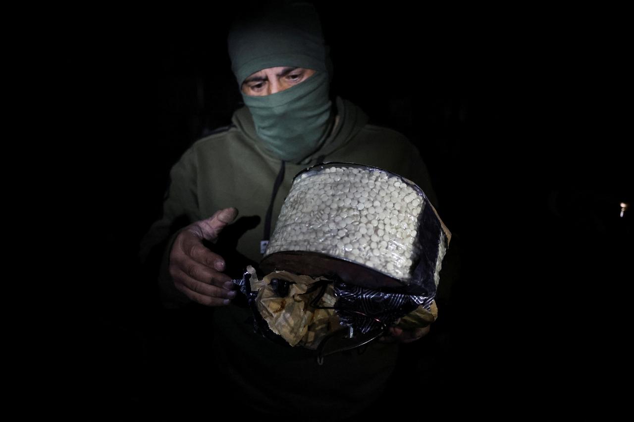 Fighter, loyal to Syria's new ruling administration, holds a box containing according to them, captagon pills, on the outskirts of Damascus