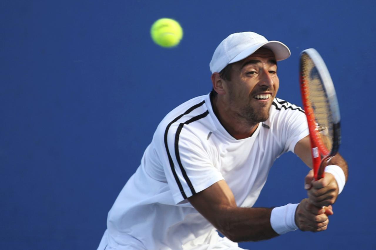 'Ivan Dodig of Croatia hits a return to Jarkko Nieminen of Finland during their men's singles match at the Australian Open tennis tournament in Melbourne January 17, 2013. REUTERS/Daniel Munoz (AUSTR