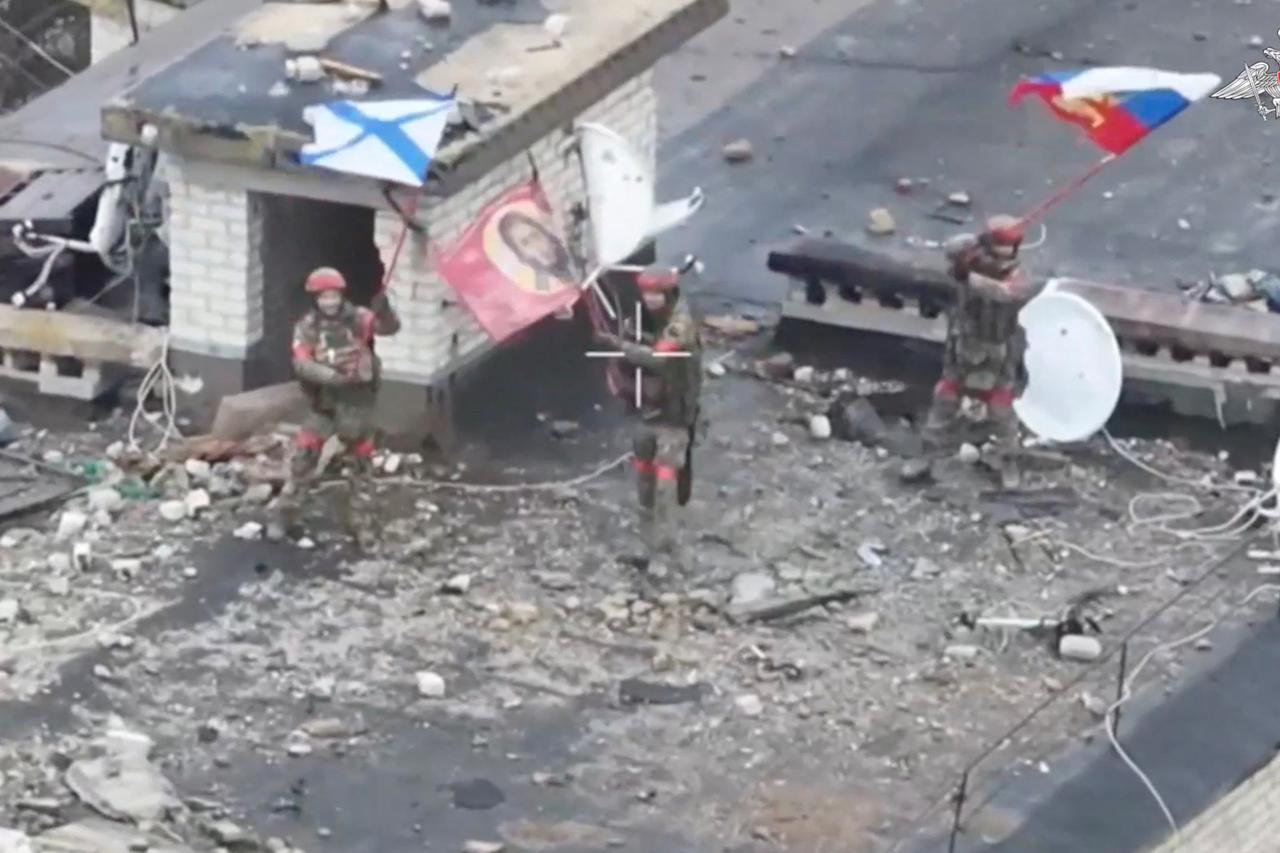 Russian service members wave flags on the roof of a building in Velyka Novosilka