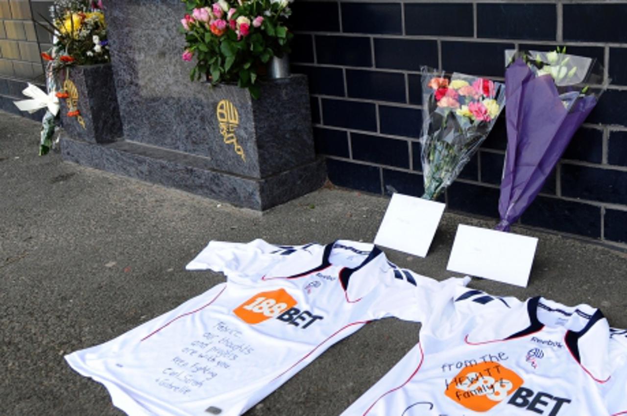 'Football shirts and flowers are seen left outside the Reebok Stadium in Bolton, north-west England on March 18, 2012 the morning after Bolton Wanderers\' English midfielder Fabrice Muamba collapsed d