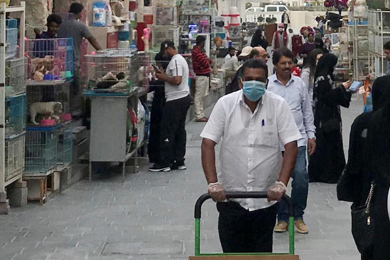 A man wears a protective face mask, following the outbreak of coronavirus, as he pushes a cart in souq Waqif in Doha