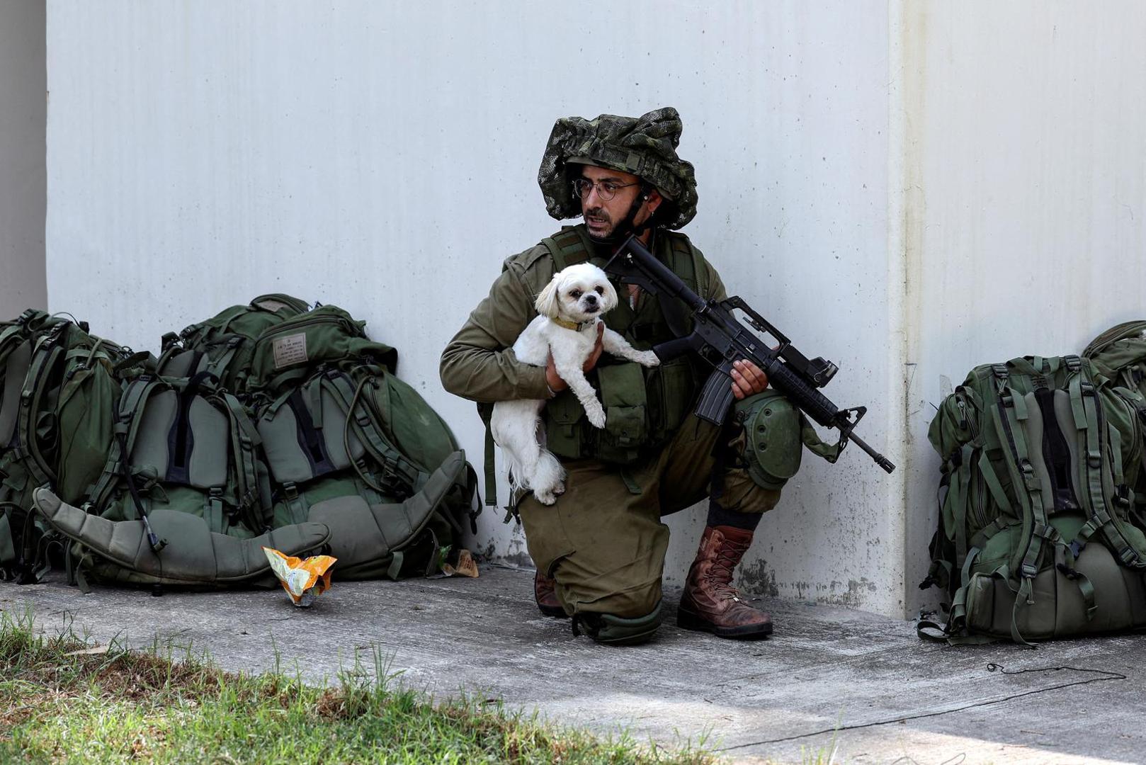 An Israeli soldier holds a rescued dog as he takes position near a bomb shelter in Kibbutz Kfar Aza, in southern Israel, October 10, 2023. REUTERS/Ronen Zvulun     TPX IMAGES OF THE DAY Photo: RONEN ZVULUN/REUTERS