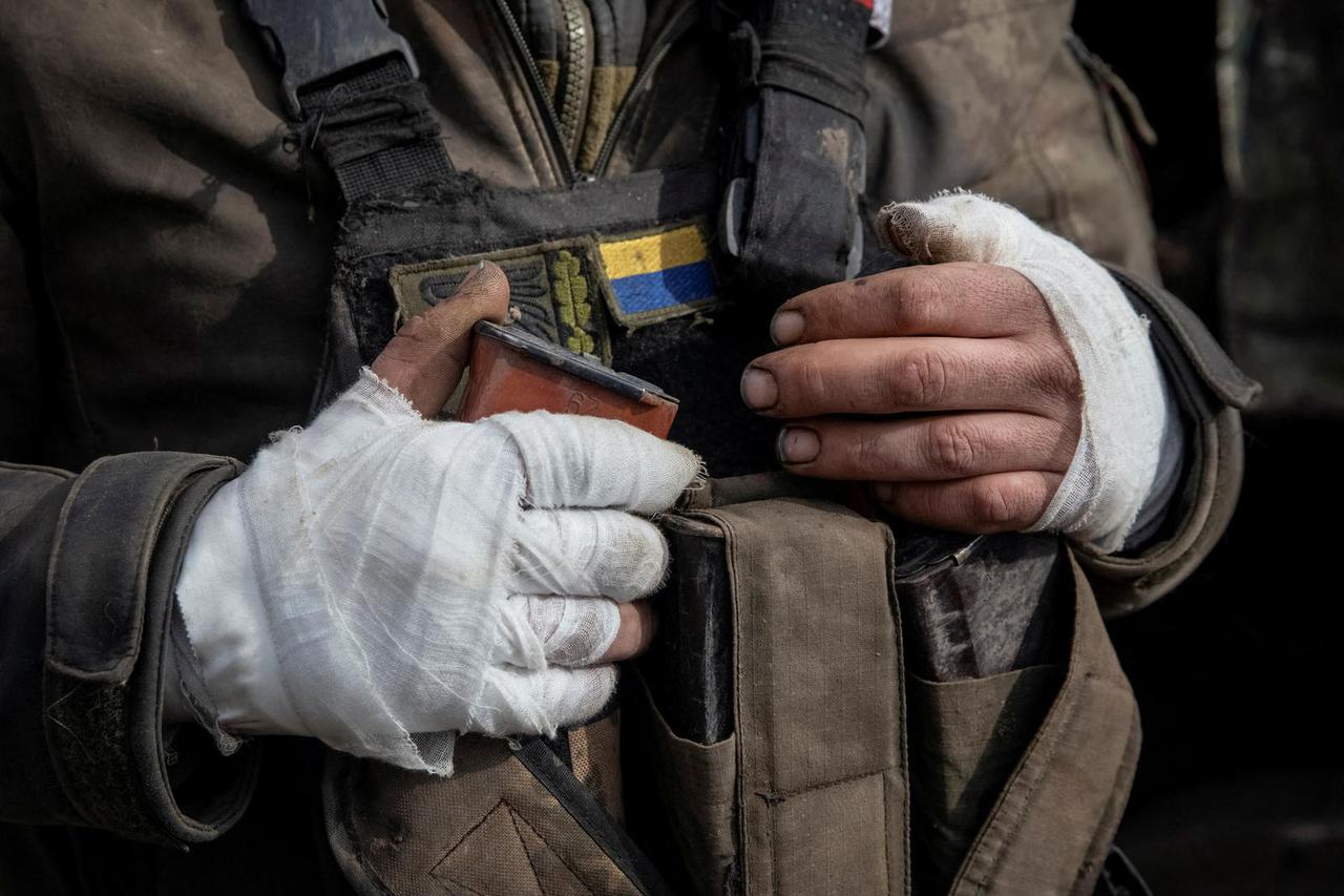 A wounded Ukrainian service member is seen near a military vehicle in Bakhmut