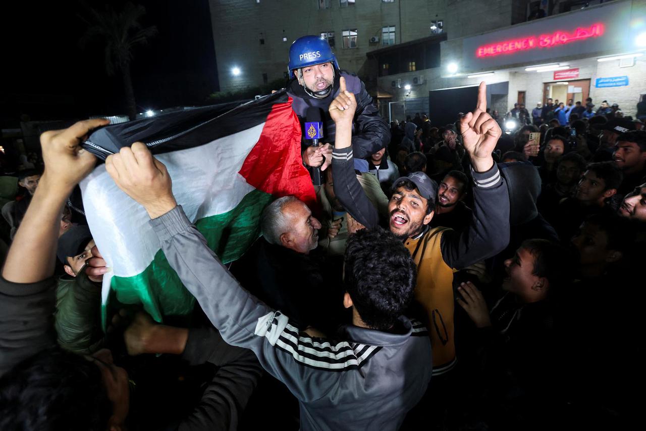 Palestinians celebrating news on a ceasefire with Israel, carry Al Jazeera correspondent Ashraf Amrah as he reports live in Deir Al-Balah in the central Gaza Strip