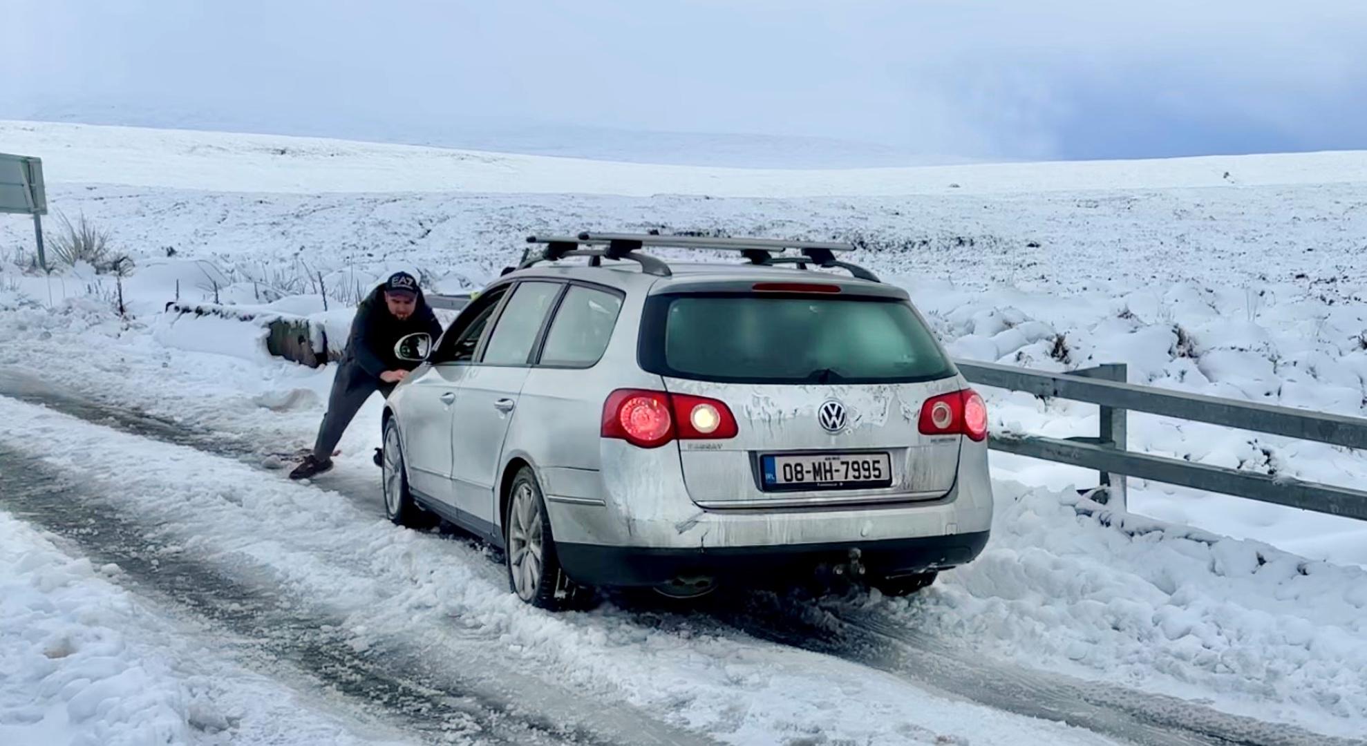 A man pushes a car stuck in the snow on the Sally Gap in the Wicklow Mountains in County Wicklow. Irish premier Simon Harris has said it is important for people to "keep their guard up" as extremely low temperatures are expected in the days ahead. Picture date: Tuesday January 7, 2025. Photo: Niall Carson/PRESS ASSOCIATION