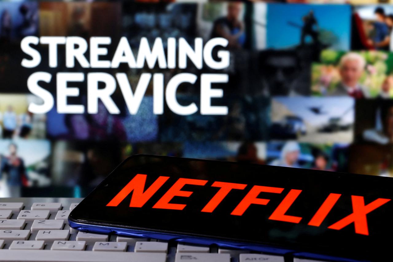 FILE PHOTO: A smartphone with the Netflix logo is seen on a keyboard in front of displayed "Streaming service" words in this illustration