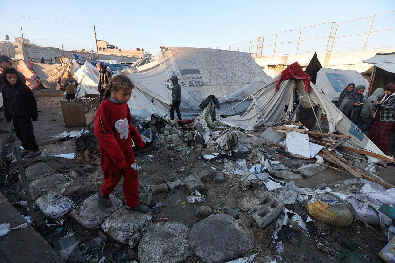 Palestinians inspect the damage at a tent camp sheltering displaced people, following an Israeli strike, in Deir Al-Balah