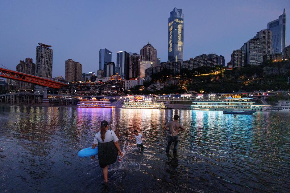 People stand in the shallow water of the Jialing river, a tributary of the Yangtze, that is approaching record-low water levels during a regional drought in Chongqing