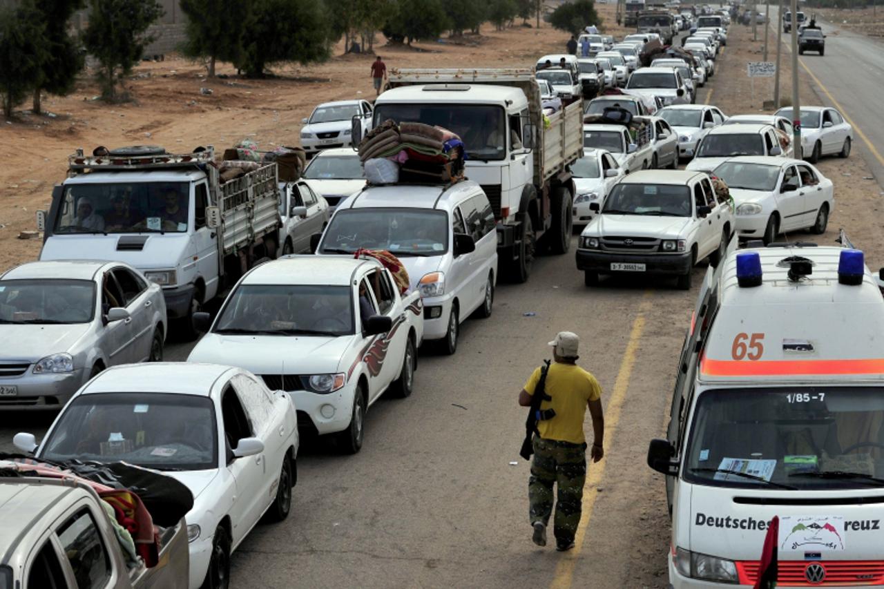 'Civilians from Sirte line up at a checkpoint outside the coastal city as they flee their homes on October 2, 2011, following an announcement by the National Transitional Council (NTC) that locals wer