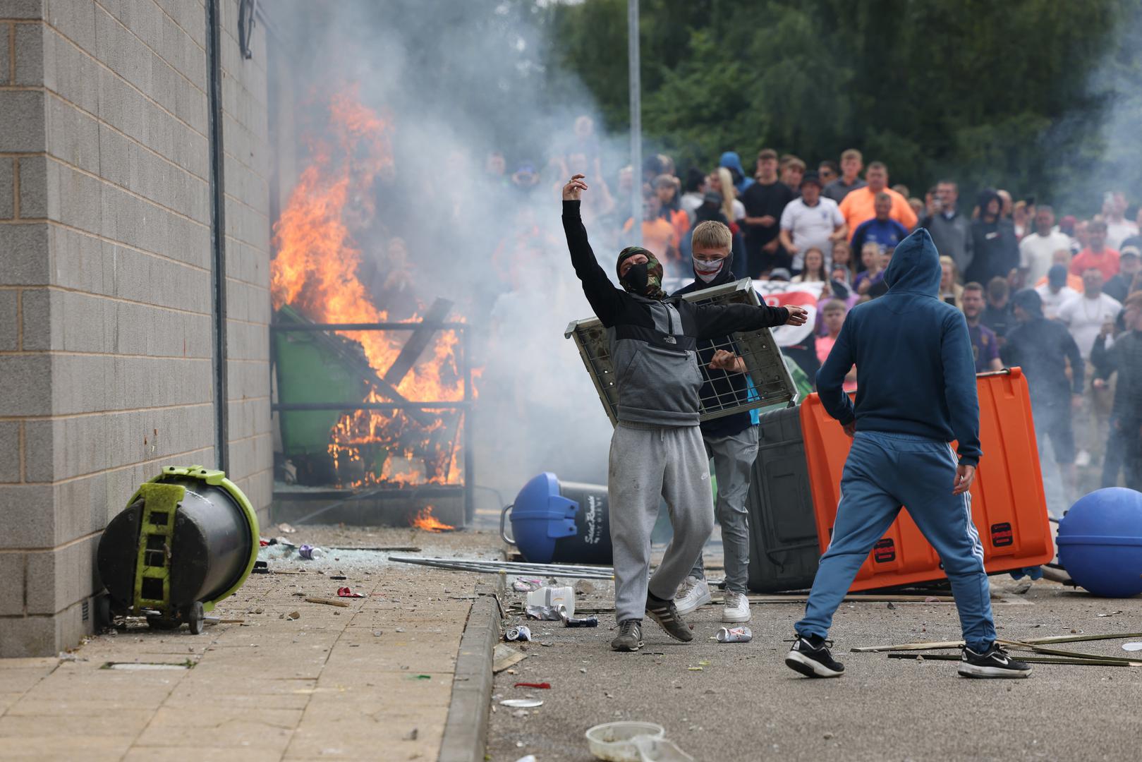 Protestors stand near burning garbage bins outside a hotel in Rotherham, Britain, August 4, 2024. REUTERS/Hollie Adams Photo: Hollie Adams/REUTERS