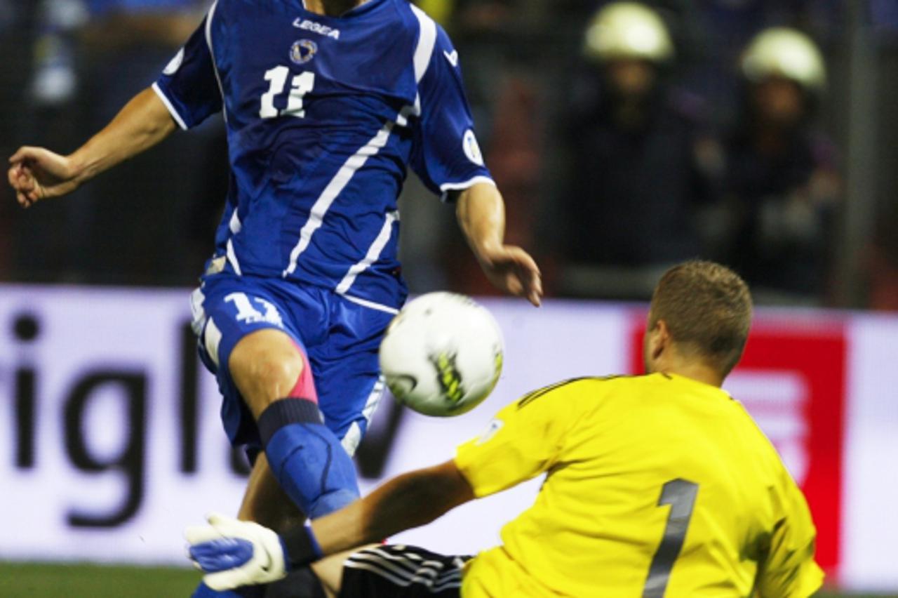 'Edin Dzeko of Bosnia (L) takes a shot at goal next to Andris Vanins of Latvia during their World Cup 2014 qualifying soccer match in Zenica, September 11, 2012. REUTERS/Dado Ruvic (BOSNIA AND HERZEGO