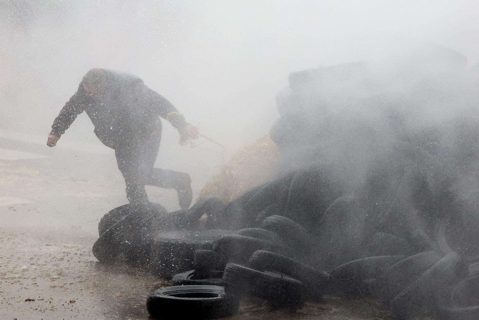 A farmer runs behind tires as he is sprayed by a water cannon during a protest of European farmers over price pressures, taxes and green regulation, on the day of an EU Agriculture Ministers meeting in Brussels, Belgium February 26, 2024. REUTERS/Yves Herman Photo: YVES HERMAN/REUTERS