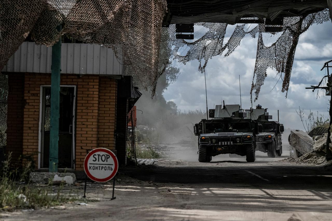 Ukrainian servicemen ride military vehicles from a crossing point at the border with Russia in Sumy region