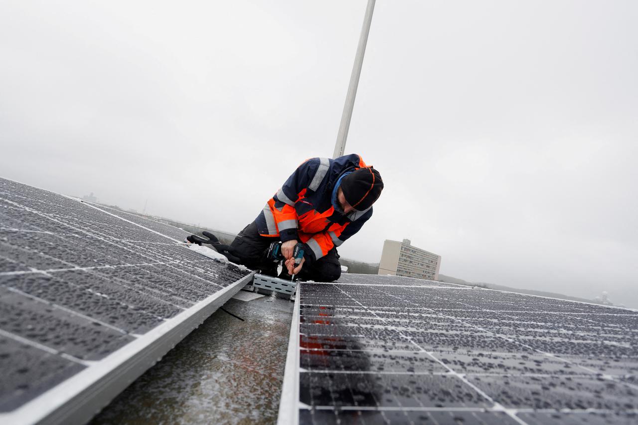 FILE PHOTO: A worker mounts solar panels on the roof of the Olympic Stadium or Olympiastadion in Berlin