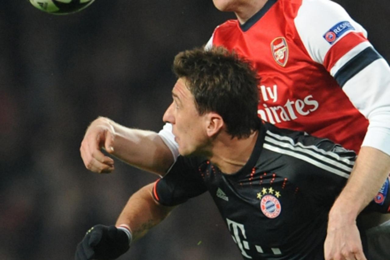 'Arsenal\'s Per Mertesacker (top) and Munich\'s Mario Mandzukic vie for the ball during the Champions League round of 16 first leg soccer match between Arsenal FC and FC Bayern Munich at Emirates Stad