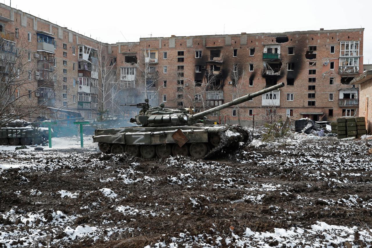 A tank with the letters "Z" painted on it is seen in front of a residential building which was damaged during Ukraine-Russia conflict in Volnovakha