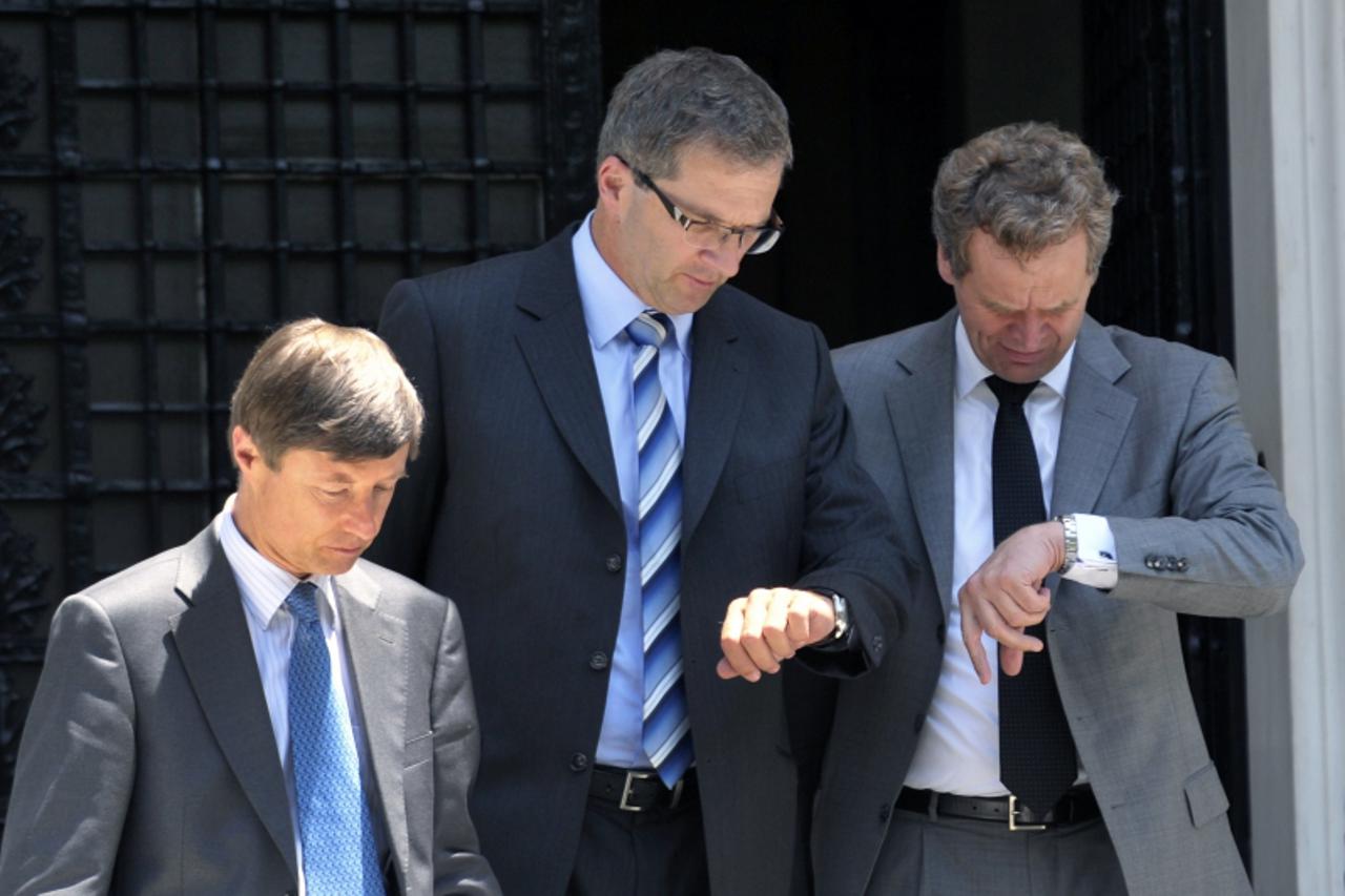 'International Monetary Fund (IMF) mission chief Poul Thomsen (R) and European Central Bank representative Klaus Masuch (C) look at their watches next to European Union official Matthias Mors (L) as t