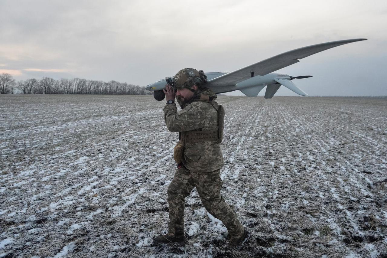 A serviceman of the Armed Forces of Ukraine carries a Shark reconnaissance drone near the town of Pokrovsk