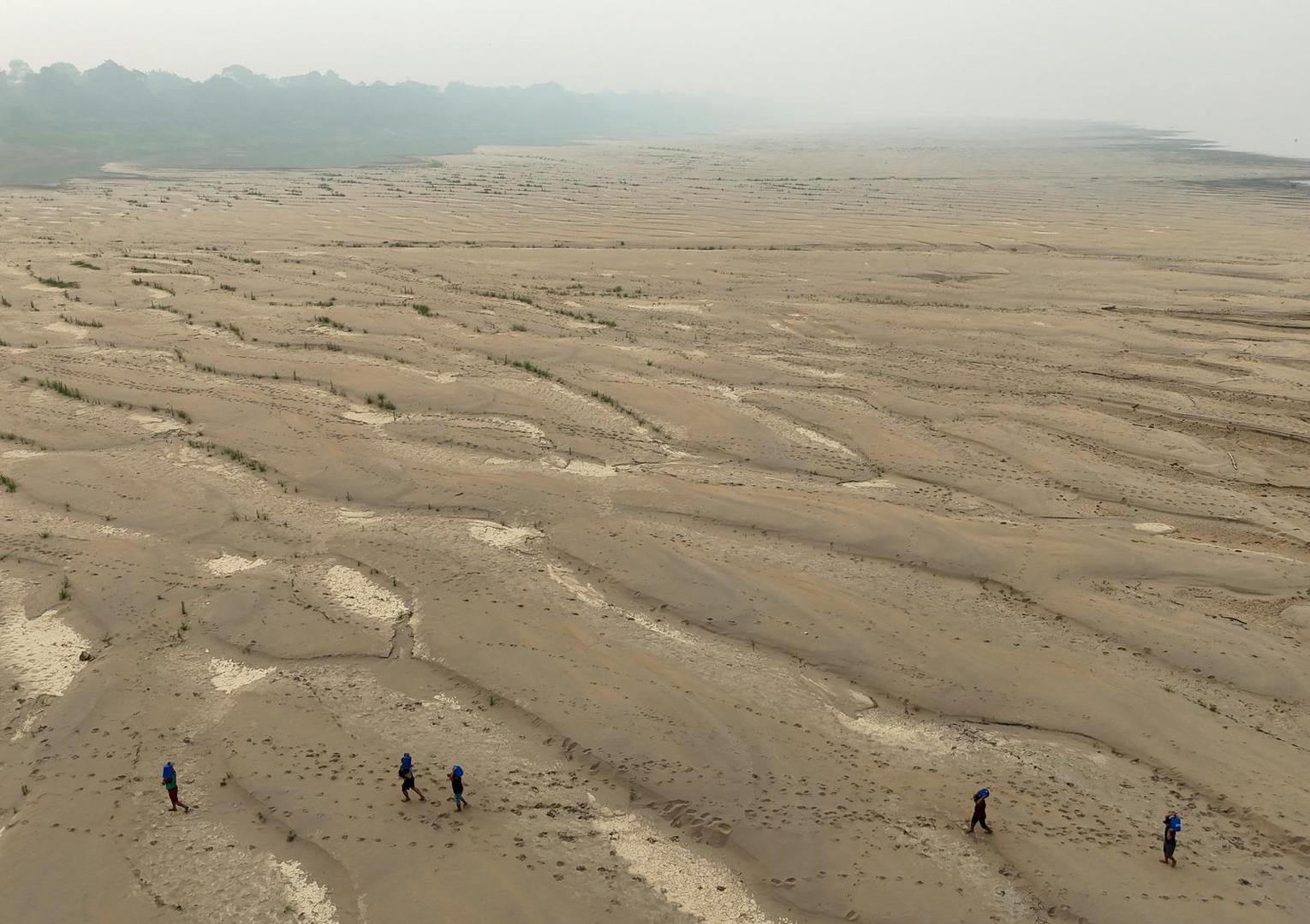 A drone view shows river dwellers carrying water gallons on the sandbanks of the Madeira river to bring to the isolated region of Paraizinho community, during the worst drought of the river in history, Humaita, Amazonas state, Brazil September 8, 2024. REUTERS/Bruno Kelly Photo: BRUNO KELLY/REUTERS