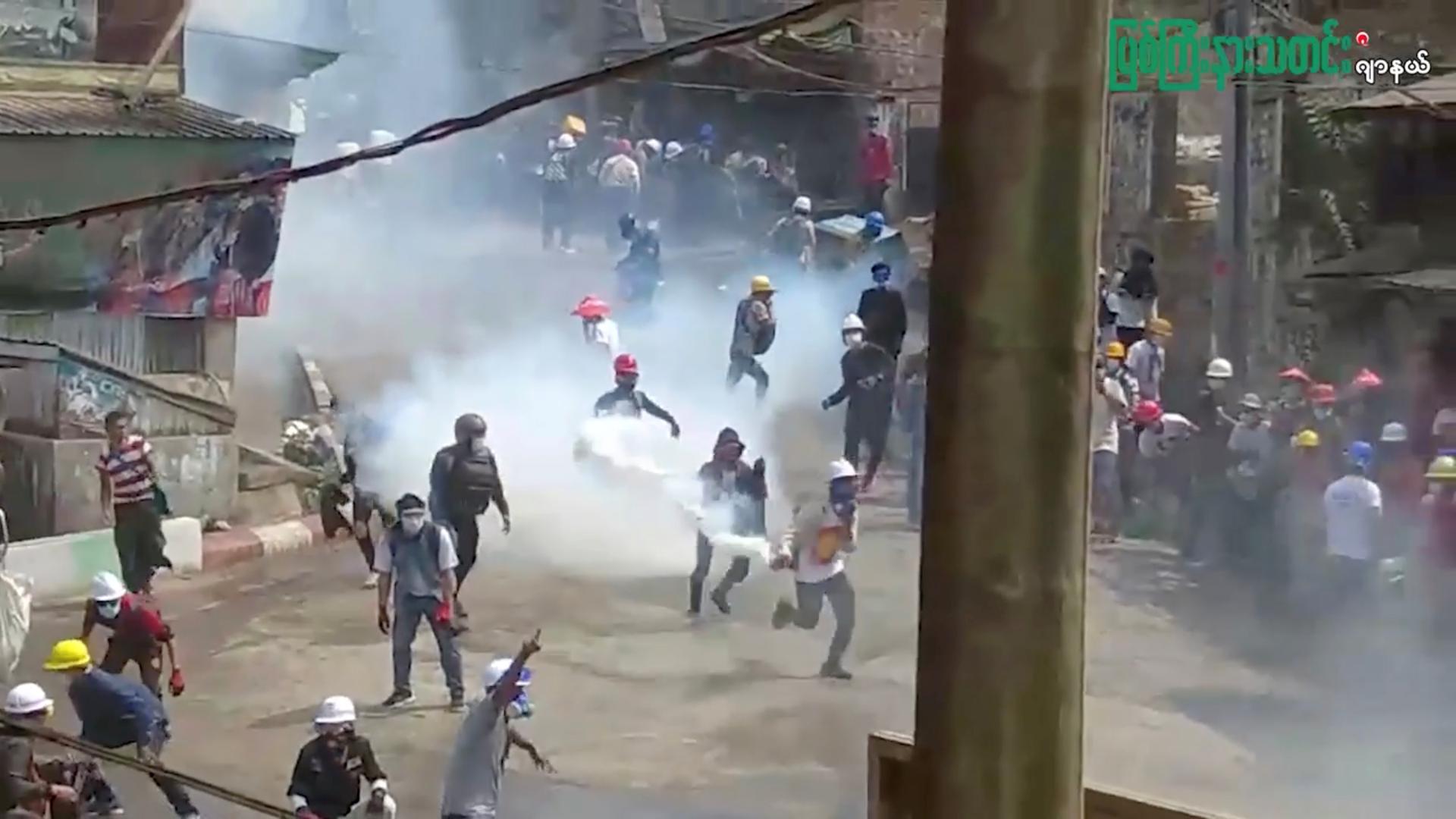 Anti-coup protest in Hpakant Anti-coup demonstrator runs with a tear gas canister that was fired into the crowd in Hpakant, Kachin, Myanmar March 14, 2021 in this still image taken from social media video. Local media reported at least one death during the protest. Myitkyina News Journal via REUTERS ATTENTION EDITORS - THIS IMAGE HAS BEEN SUPPLIED BY A THIRD PARTY. MANDATORY CREDIT. MYITKYINA NEWS JOURNAL