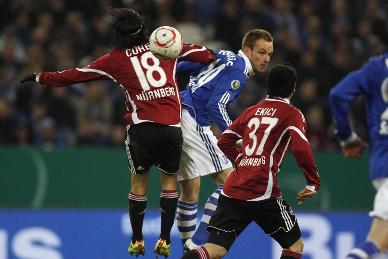 \'Nuremberg\'s Almog Cohen and Schalke 04\'s Ivan Rakitic (C) jump for the ball during their German soccer cup (DFB-Pokal) quarter-final match in Gelsenkirchen January 25, 2011. REUTERS/Ina Fassbender