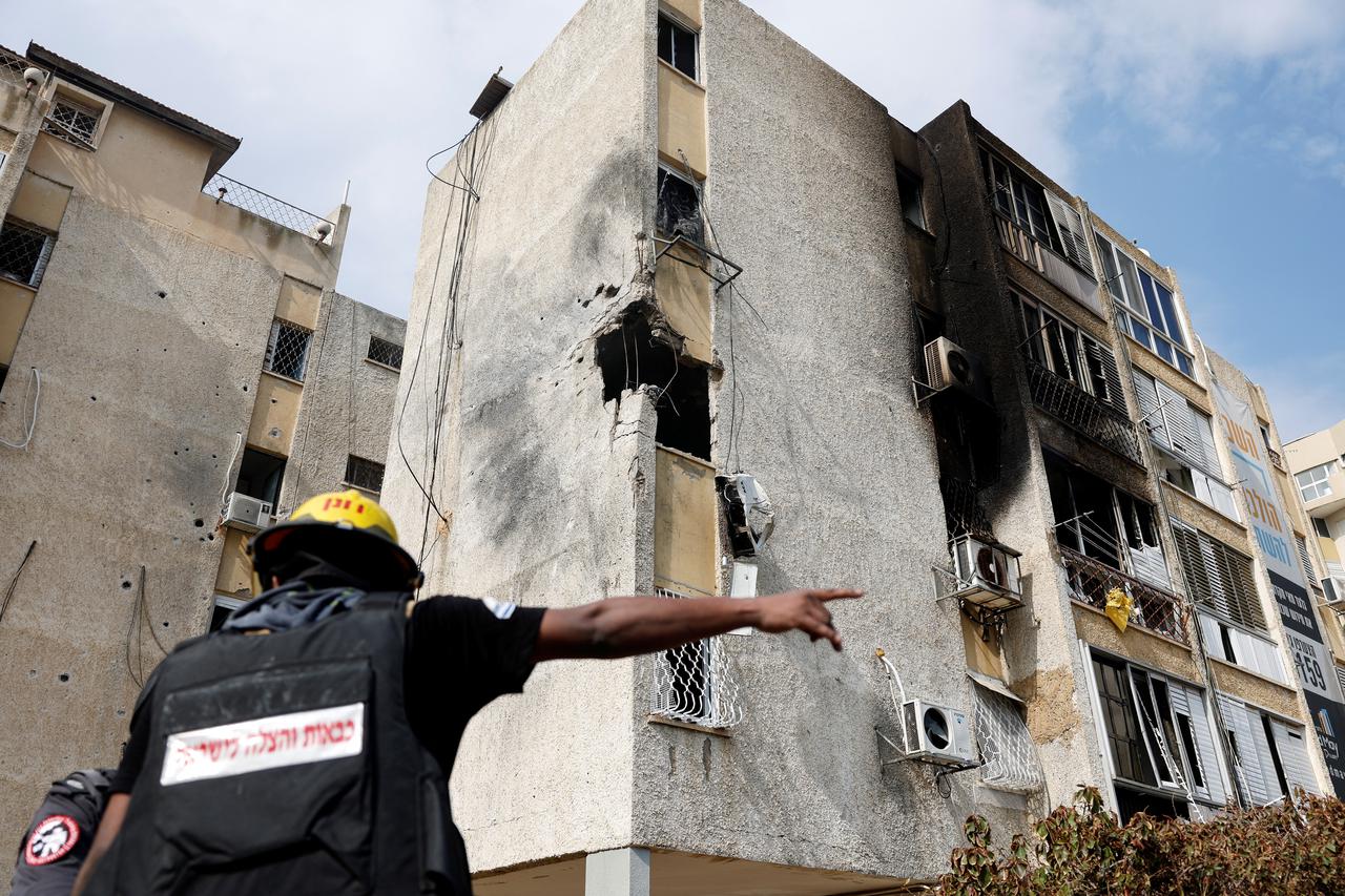 A firefighter gestures in front of a damaged building after a rocket, launched from the Gaza Strip, landed in Ashkelon