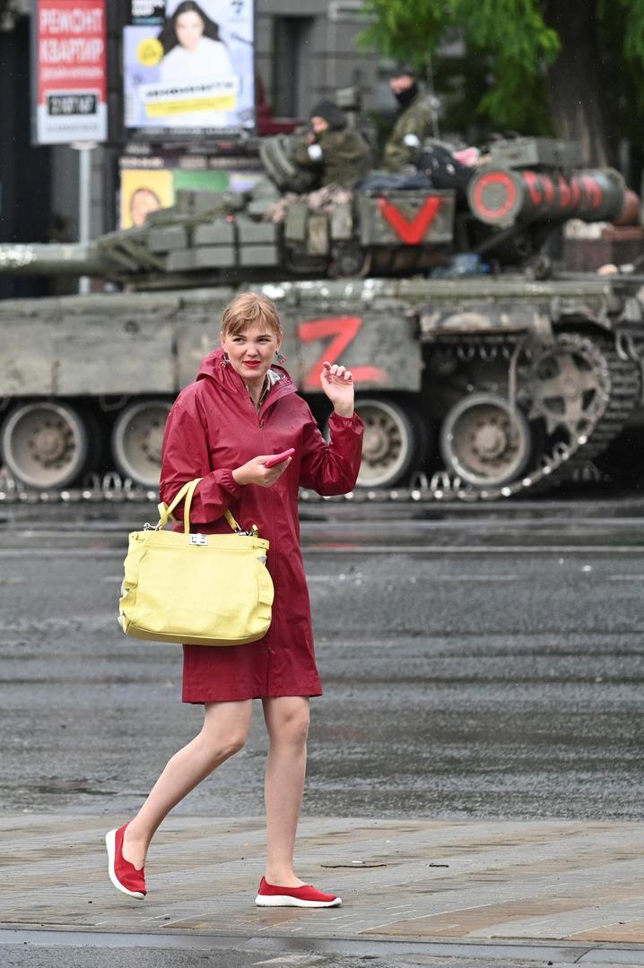 A woman walks past fighters of Wagner private mercenary group in a street near the headquarters of the Southern Military District in the city of Rostov-on-Don, Russia, June 24, 2023. REUTERS/Stringer Photo: Stringer/REUTERS