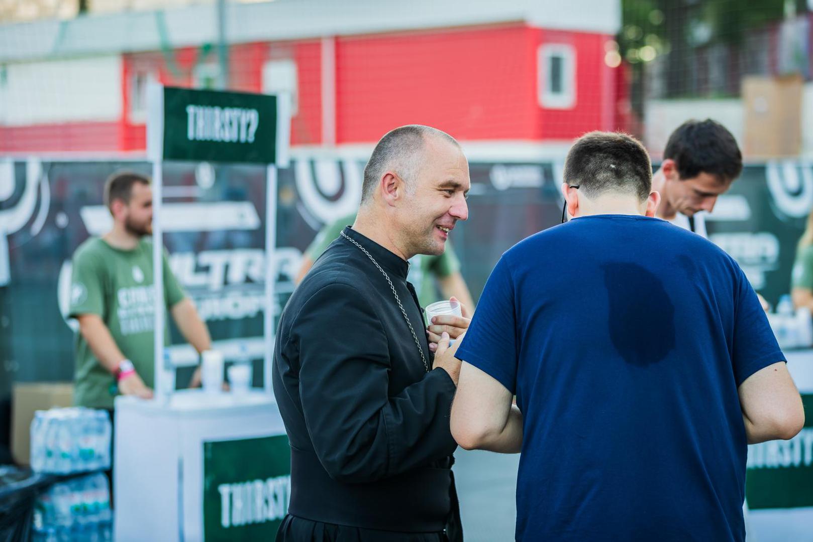 Oni partijanerima dijele vodu na štandu na kojemu velikim slovima piše "Žedni?" na engleskom jeziku.